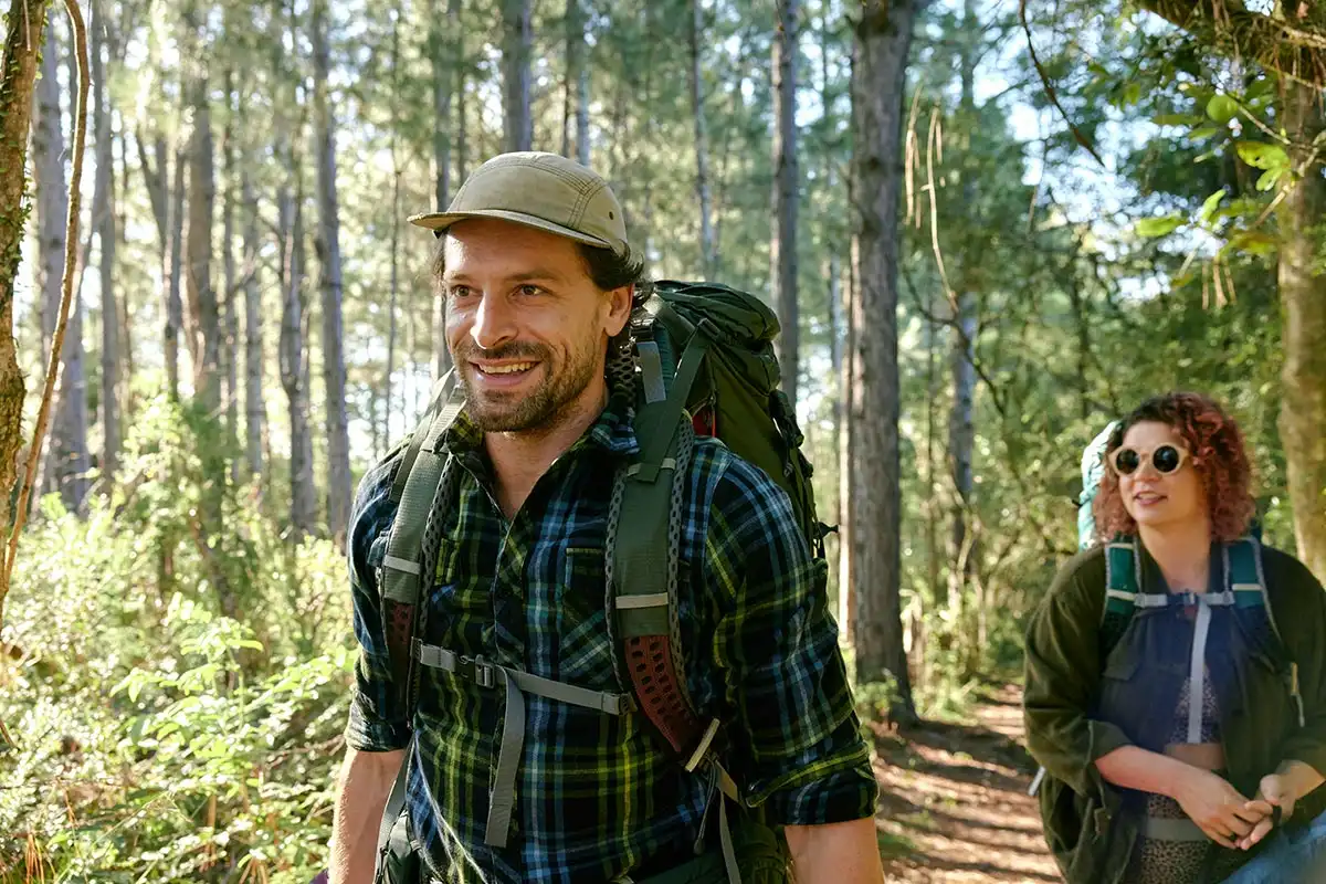 A man and woman stroll through a vibrant autumn forest, enjoying the beauty of nature during a sober fall outing