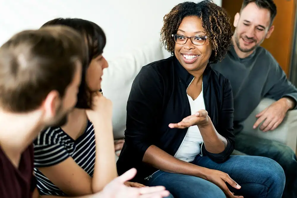 A woman engages a group of individuals in discussion during a session of the Partial Hospitalization Program