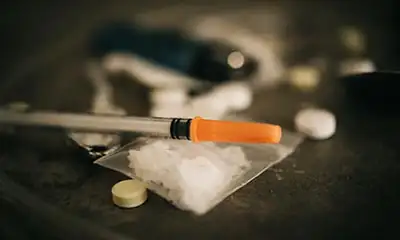 An orange and white cigarette placed on a table, highlighting the themes of substance use and the risks associated with heroin