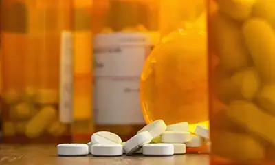 Prescription bottles and pills positioned on a table, illustrating the focus on opioids