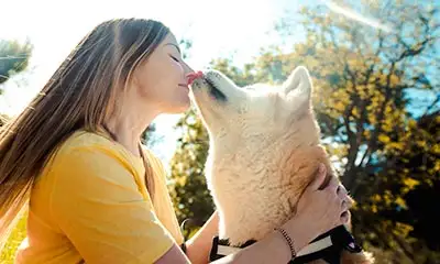 a woman wearing yellow shirt kissing her dog during animal therapy from drug rehab in riverside california