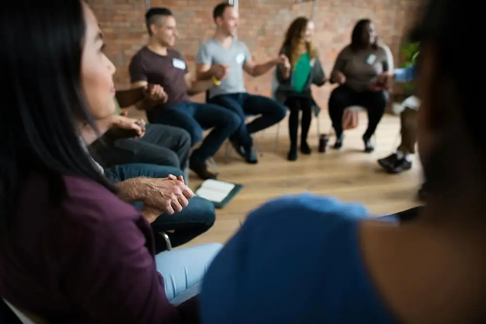 people in circle holding hands during a  group therapy from drug rehab center in riverside california