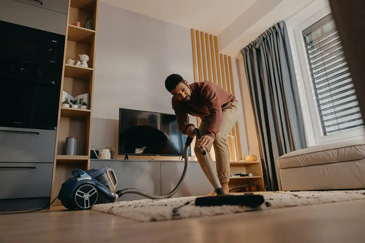 a man vacuuming the rug, establishing positive habits