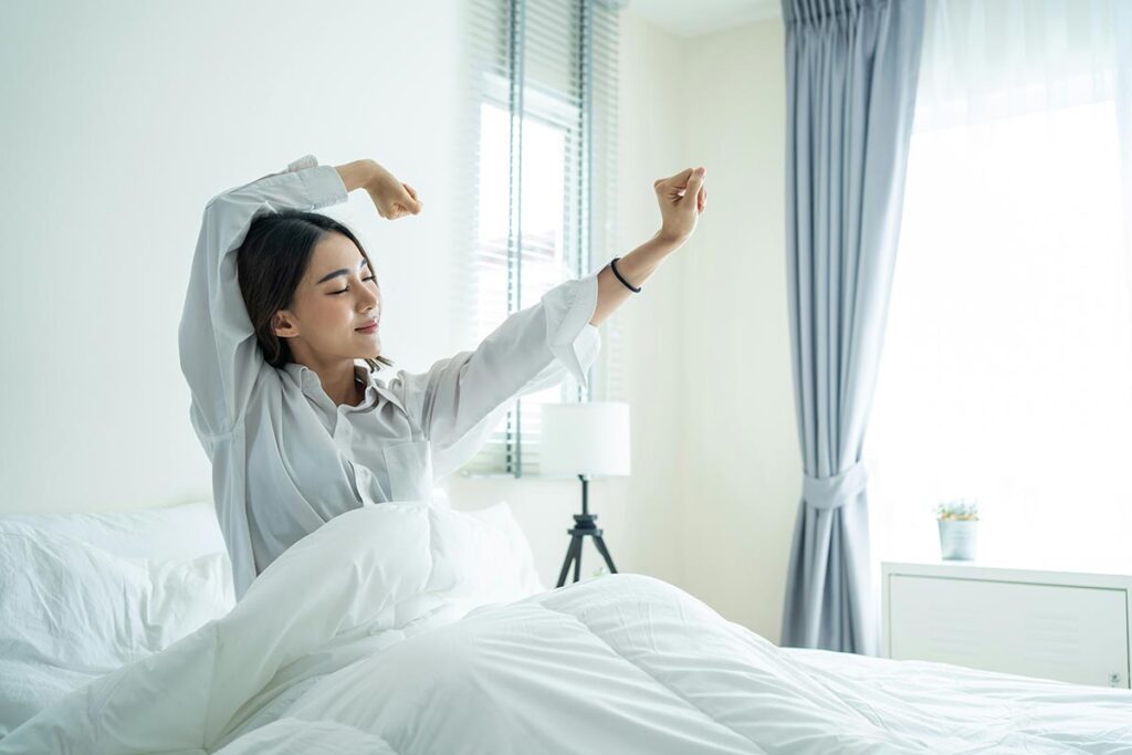 a woman stretching in bed embracing a peaceful morning routine
