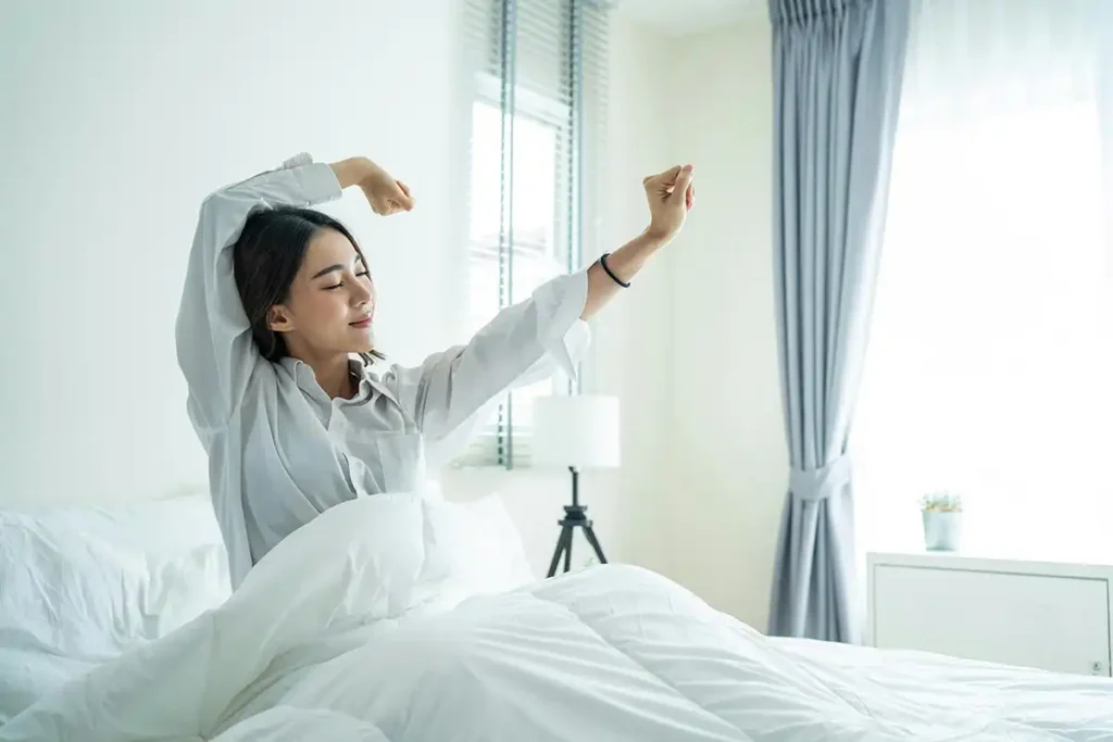 a woman stretching in bed embracing a peaceful morning routine