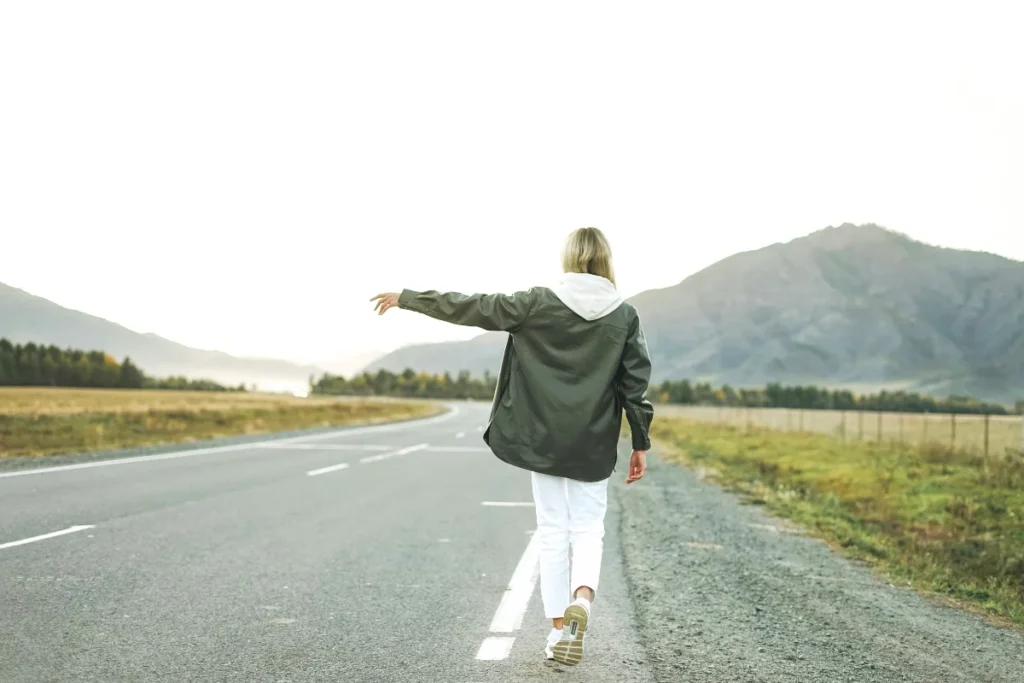 A woman walks along the road, arms outstretched, embodying freedom and moving forward without resentment