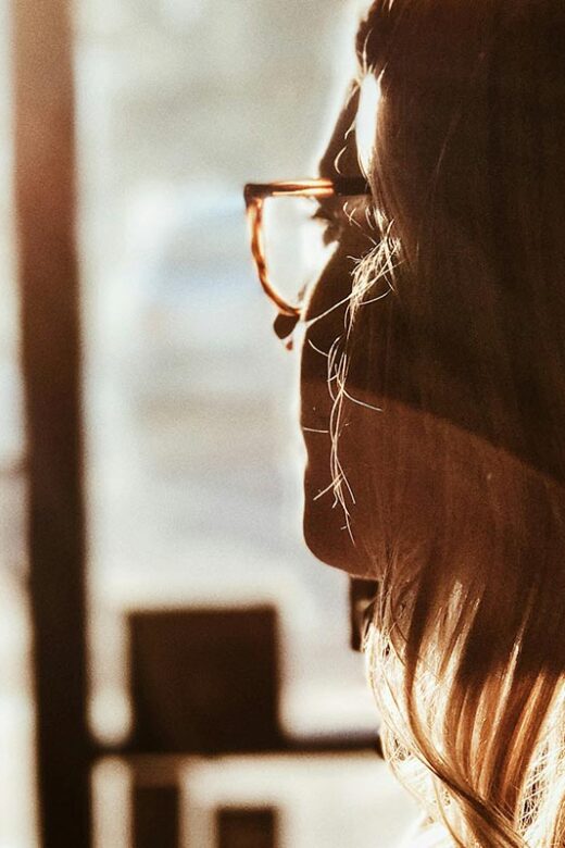 A woman looking out a window, appearing thoughtful or contemplative