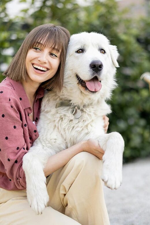 portrait of a woman hugs with her adorable white dog at backyard outdoors