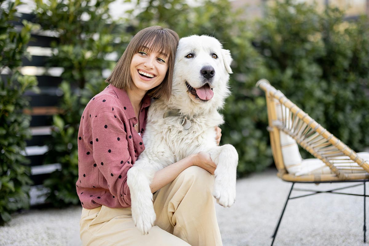 portrait of a woman hugs with her adorable white dog at backyard outdoors