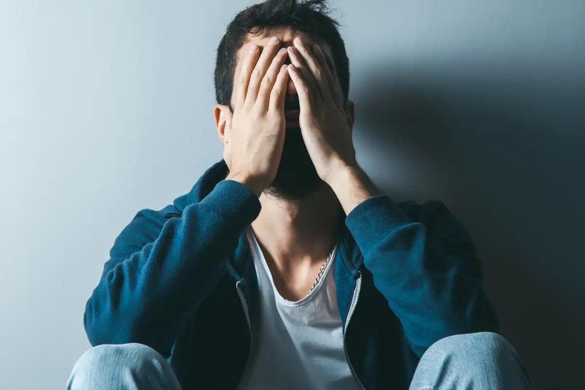 sad man hand in face sitting in the hallway