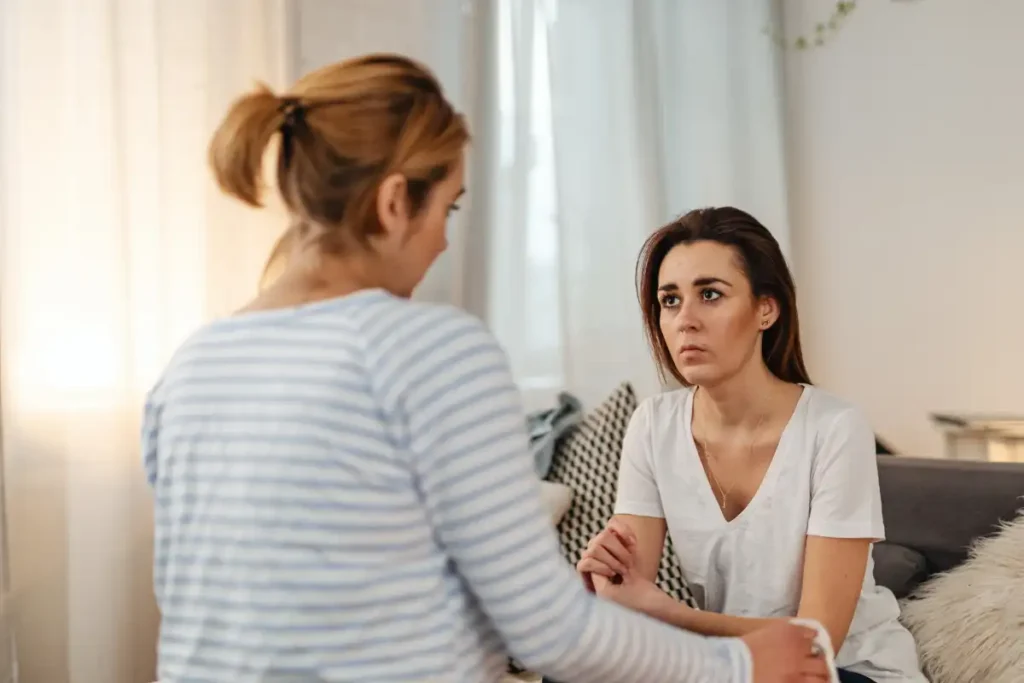 A Woman Sitting on a Couch while Listening to a Person Talking
