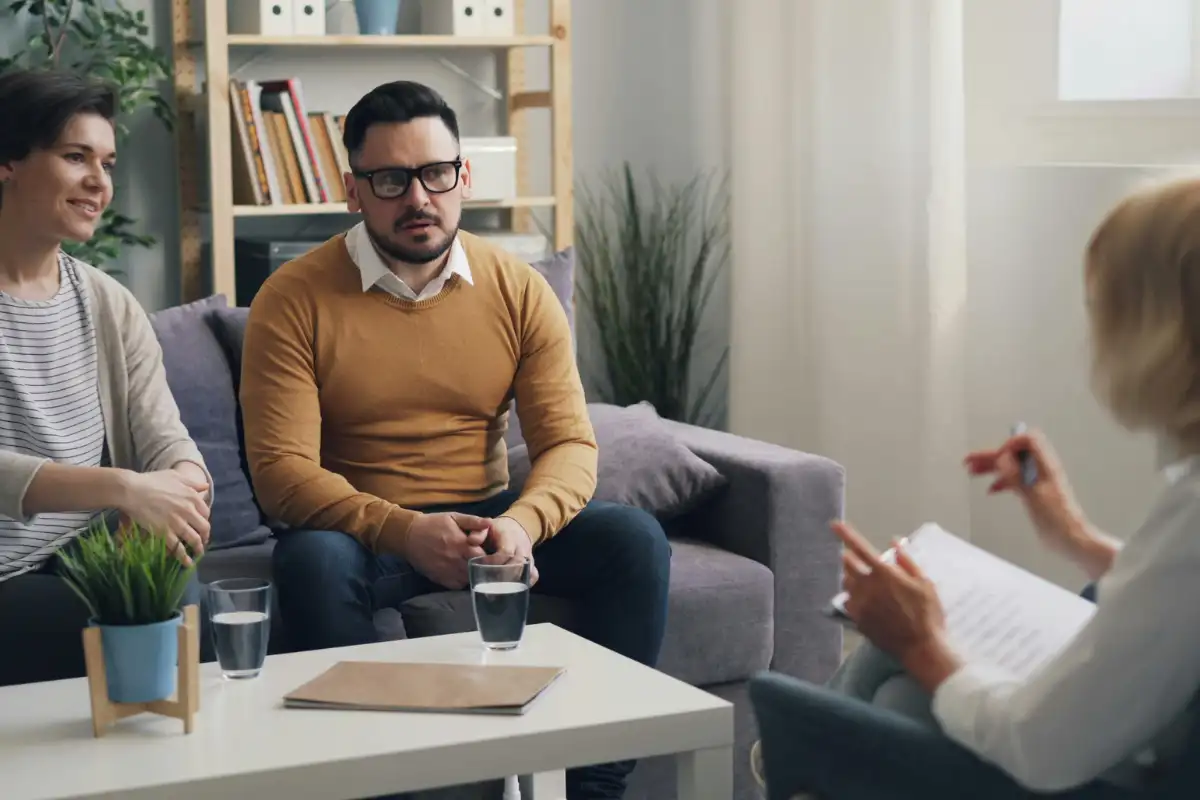 A woman and two men sitting on a couch in a living room