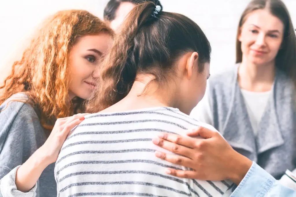 Support group patients comforting woman at therapy session