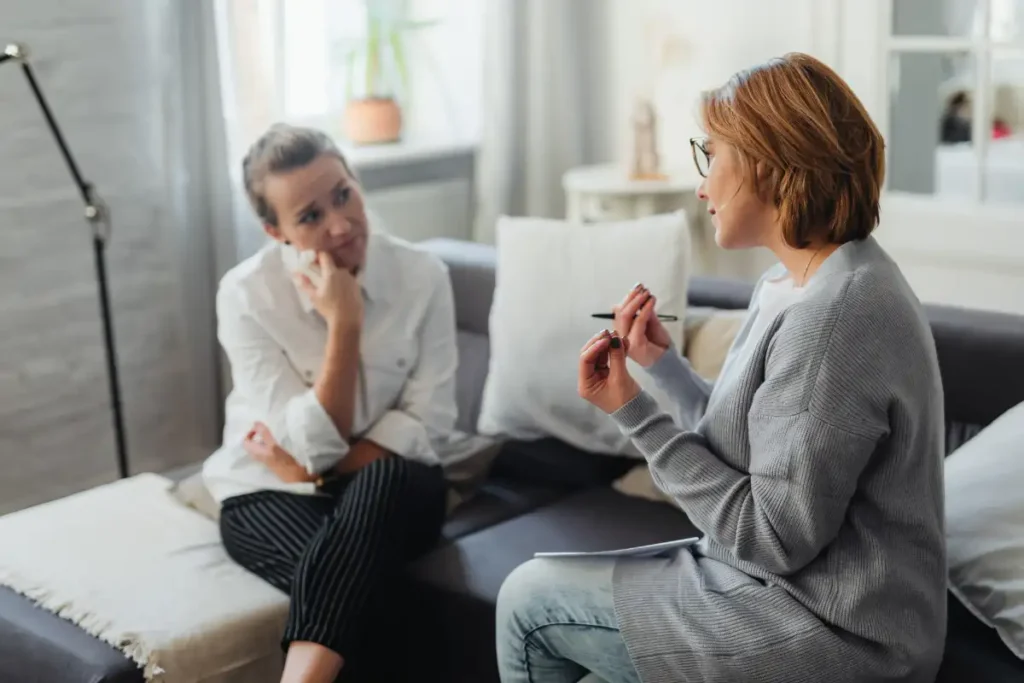Woman in Gray Long Sleeves Wearing Black Framed Eyeglasses Talking to Woman in White Long Sleeves