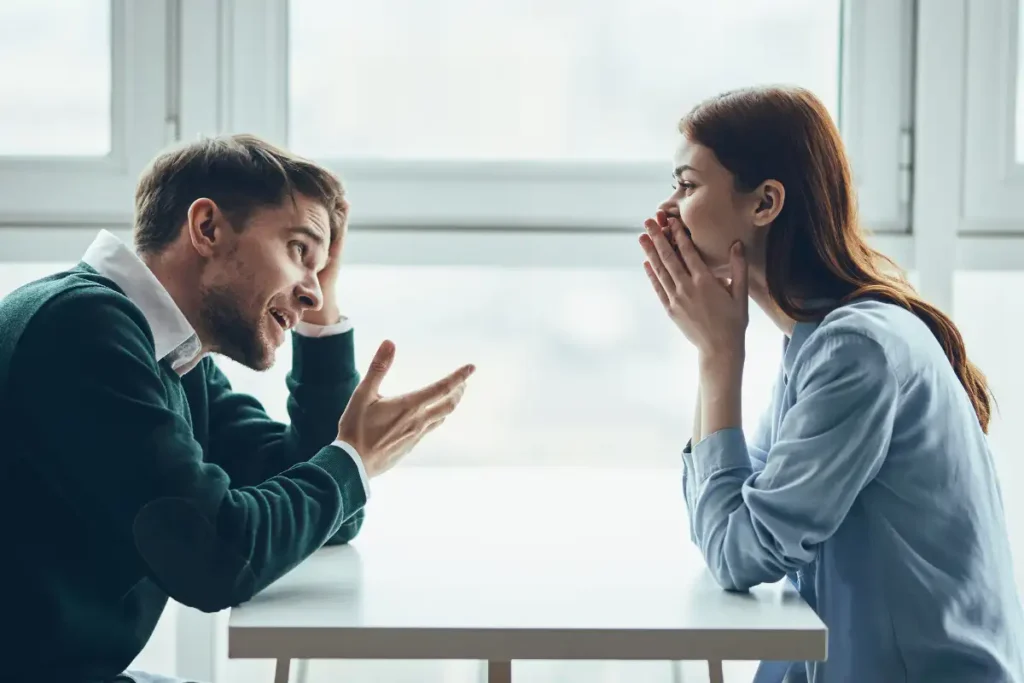 A man and a woman are sitting at a table talking, quarreling with each other, a real quarrel, household issues