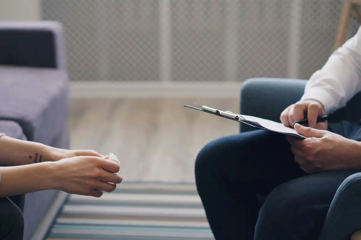 A man and woman sitting in a chair talking to each other during psychotherapy