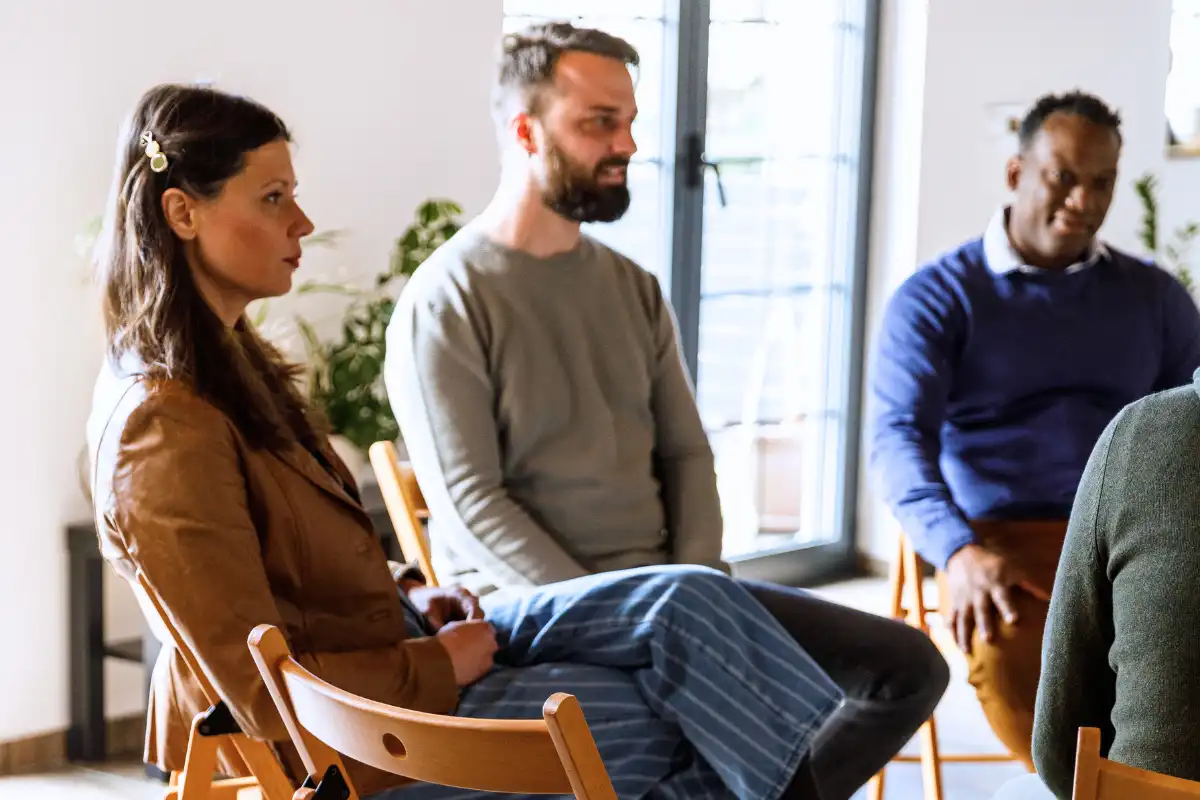Group of people sitting in circle, talking during group therapy