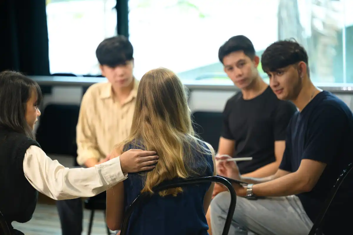 Support group session with diverse young adults sharing experiences and offering encouragement