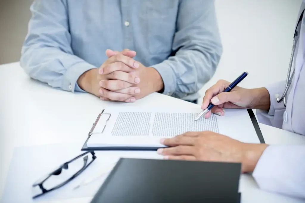 Doctor Filling Up Form While Consulting Patient