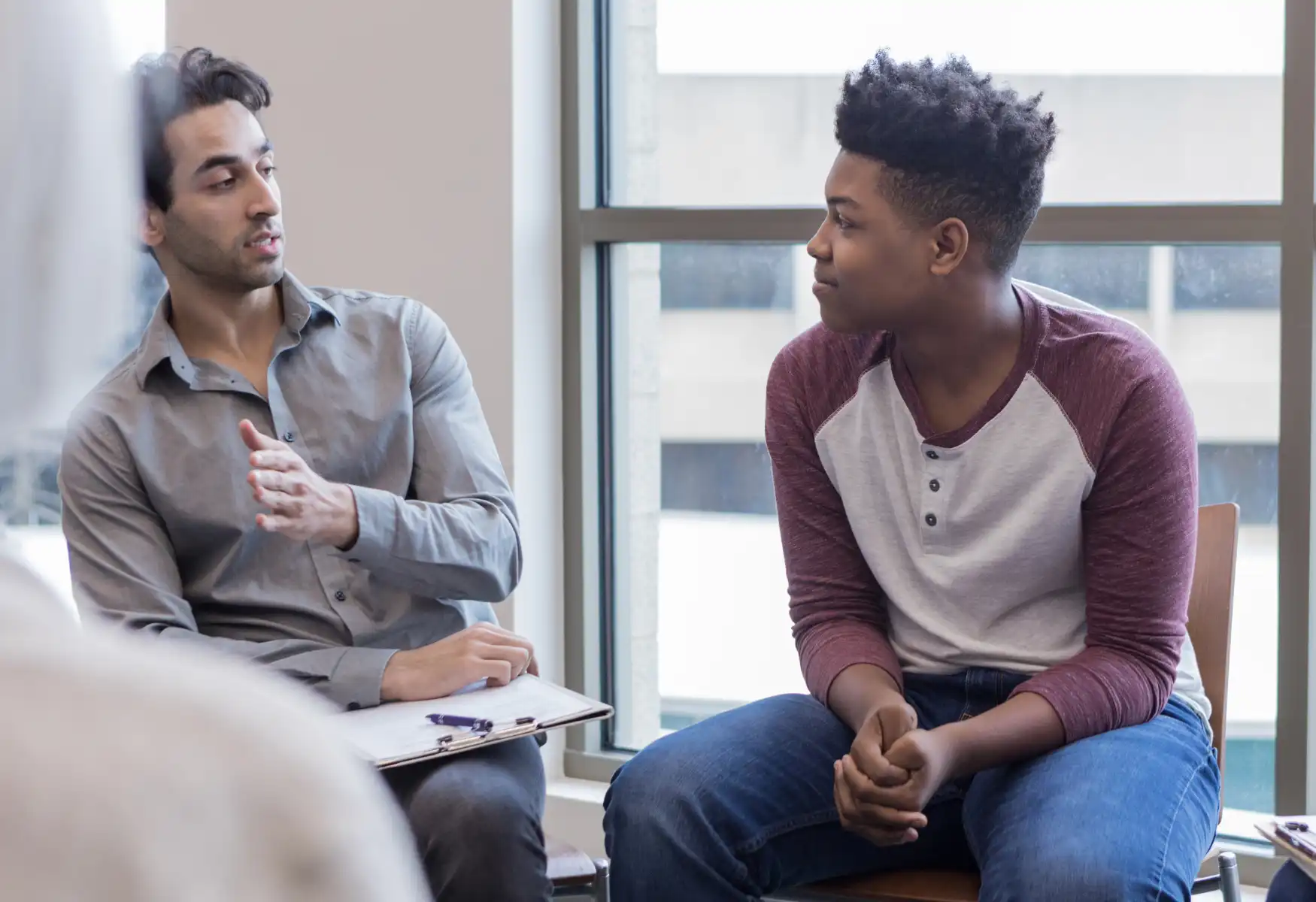 Mid adult male therapist gives teen boy counsel
