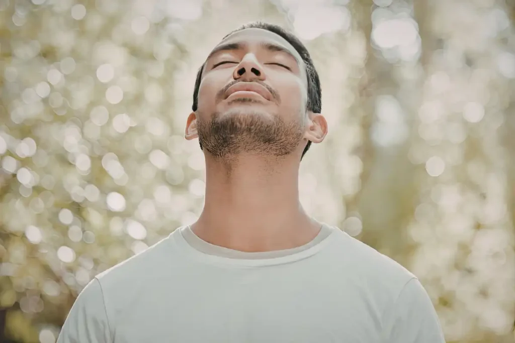 A man taking a deep breath in a serene natural setting