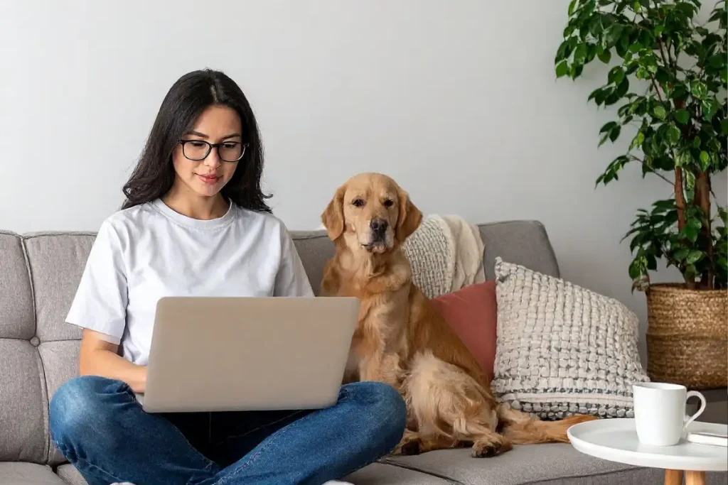 Woman Using Laptop with her Dog on Couch