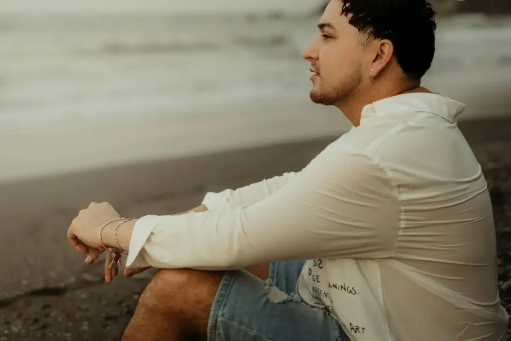 Contemplative Man Sitting on Beach at Sunset