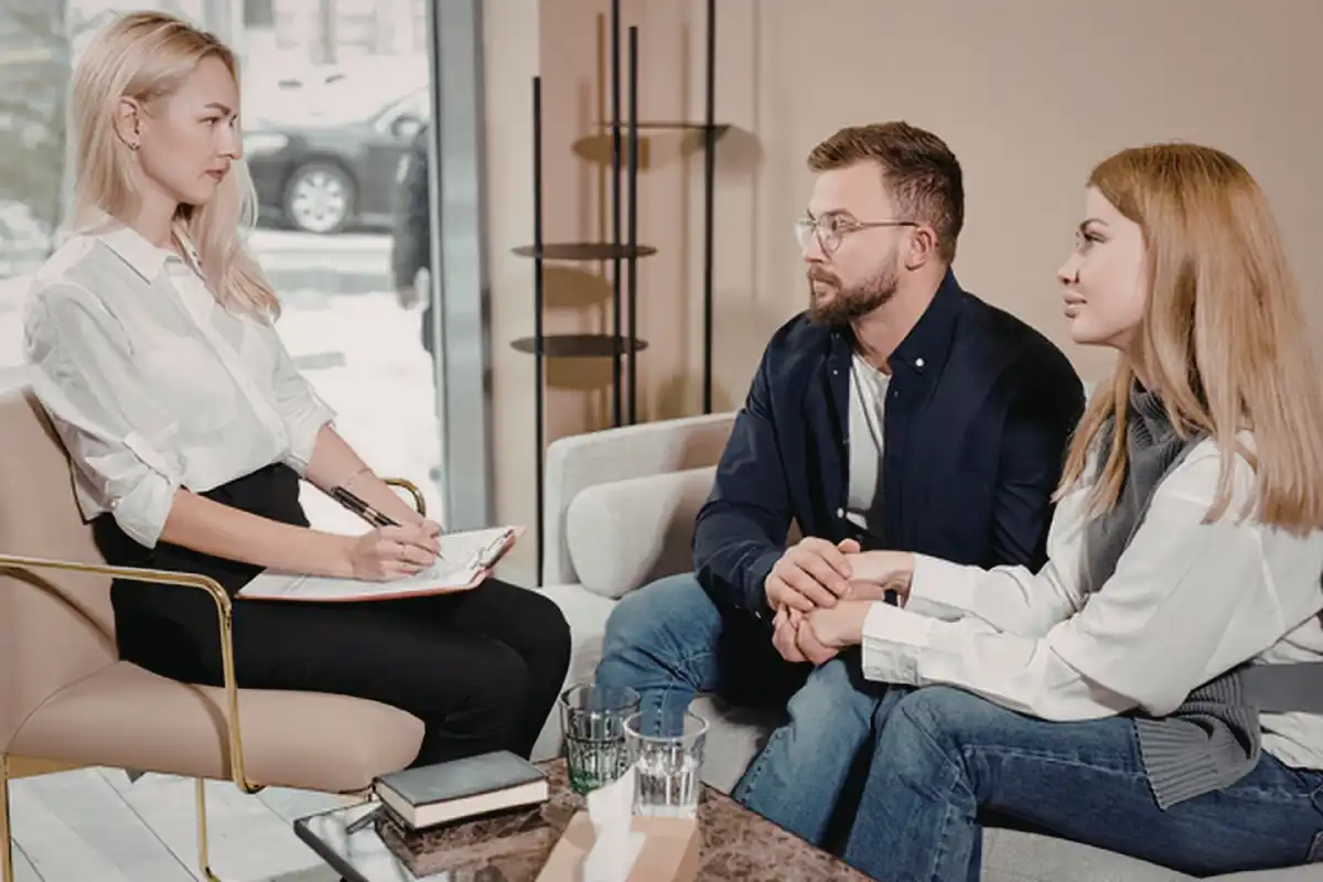 Couple engaged in counseling session with therapist taking notes in modern office setting together