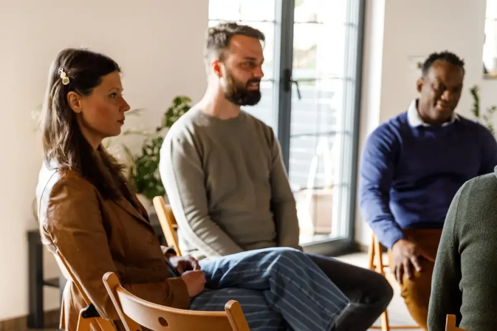 Group of people sitting in circle, talking during group therapy