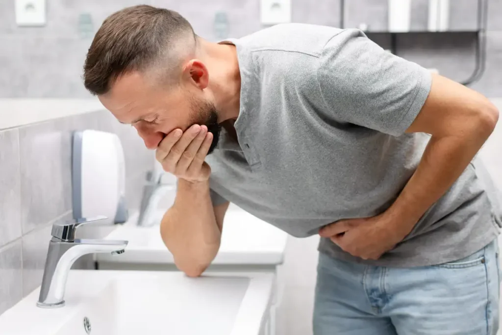Man Suffering from Nausea over Sink in Bathroom