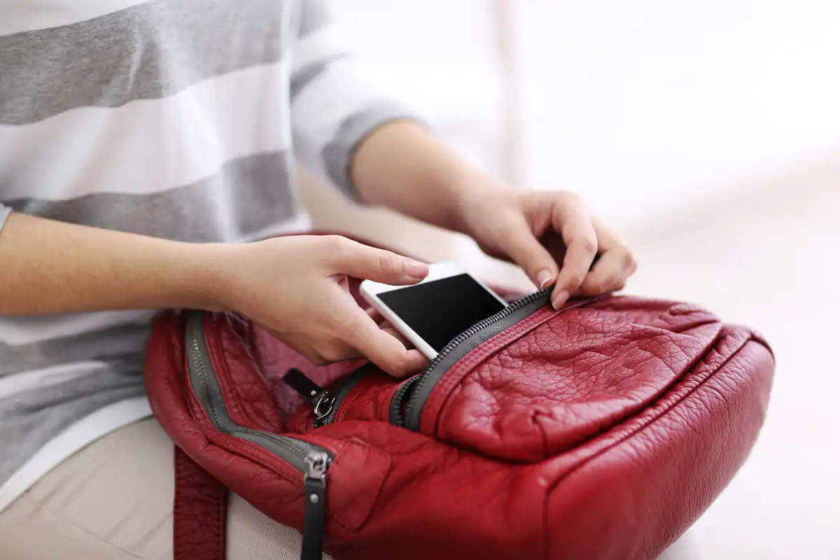 Woman Putting Mobile Phone in Red Leather Backpack