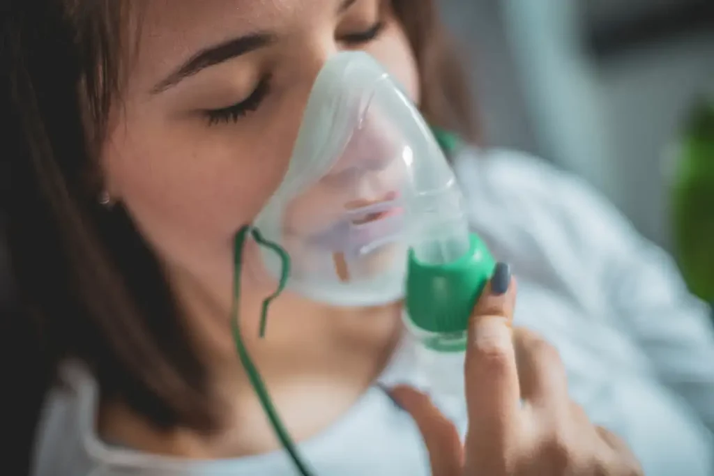 Closeup view of a woman's face who is using an inhaler to support her breathing