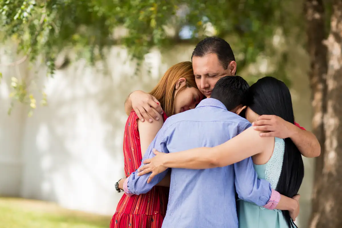 Latin family praying and embracing outdoors