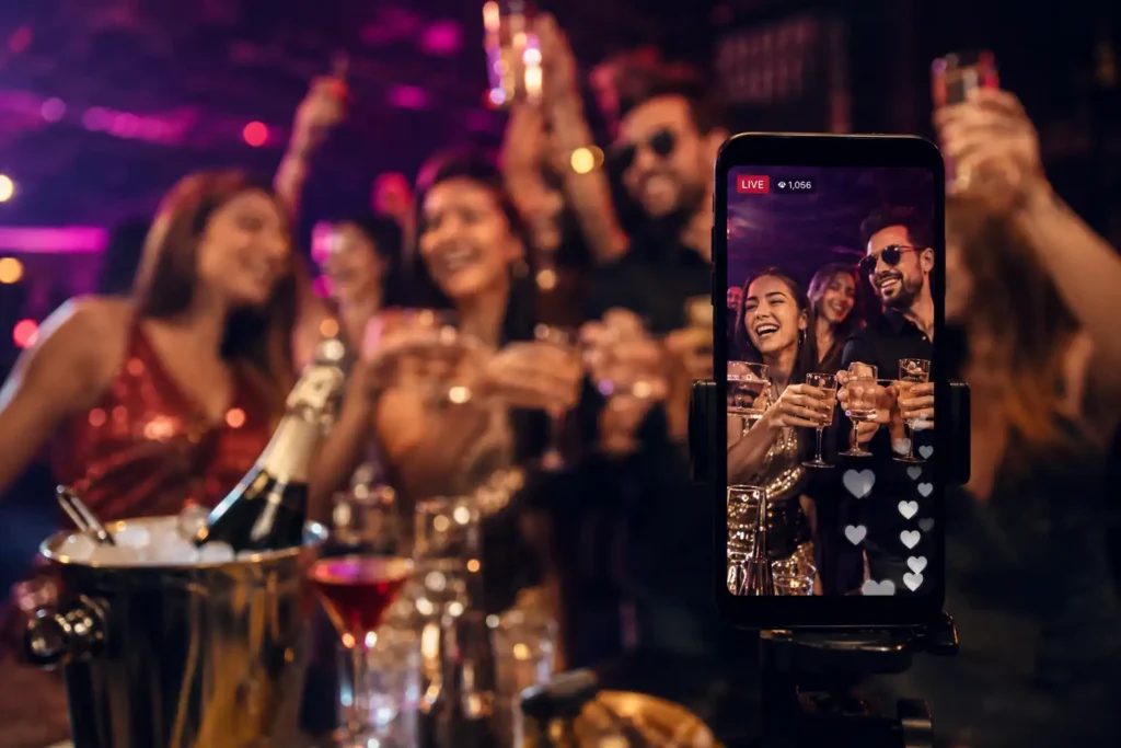 Young adults at a nightlife party drinking while a smartphone records the celebration for social media