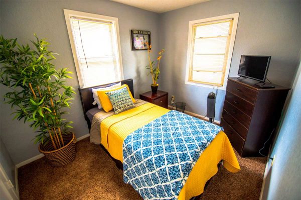 10 Acre Ranch BLU Private Cottages Facility Interior single bedroom with yellow bedsheet
